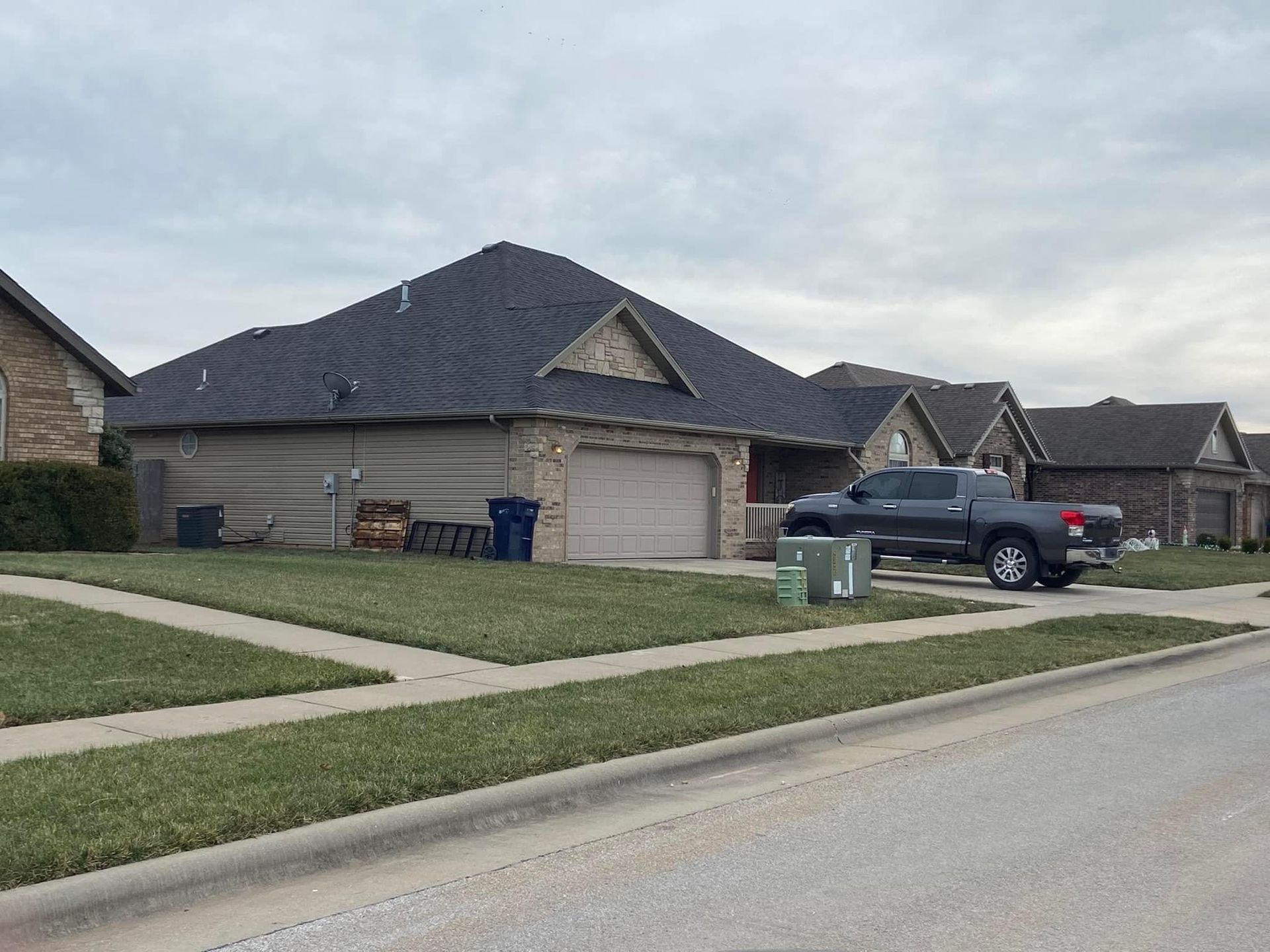 A black truck is parked in front of a house in a residential neighborhood.