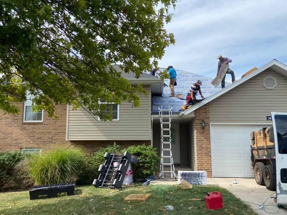 A group of people are working on the roof of a house.