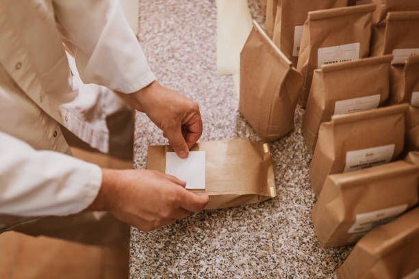 A person is putting a label on a brown paper bag.