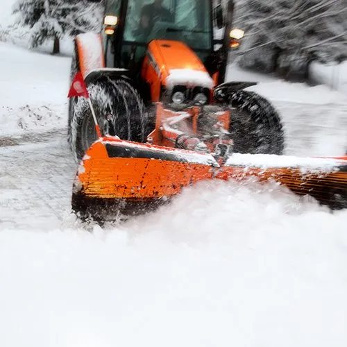 Orange tractor plowing snow, outdoors.