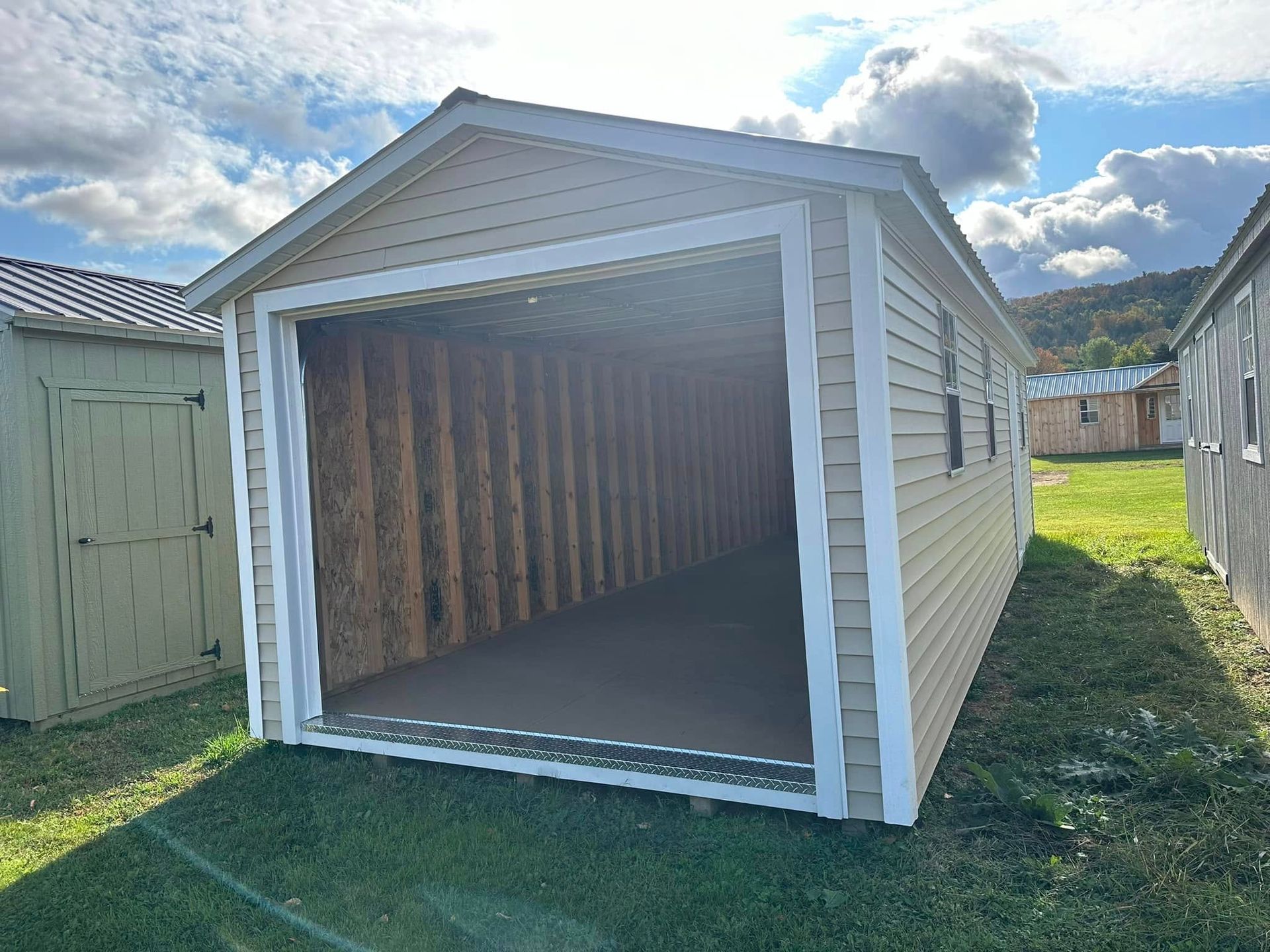 A small shed with the door open is sitting in the grass.