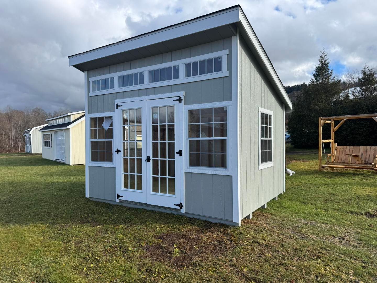 A small shed is sitting in the middle of a grassy field.