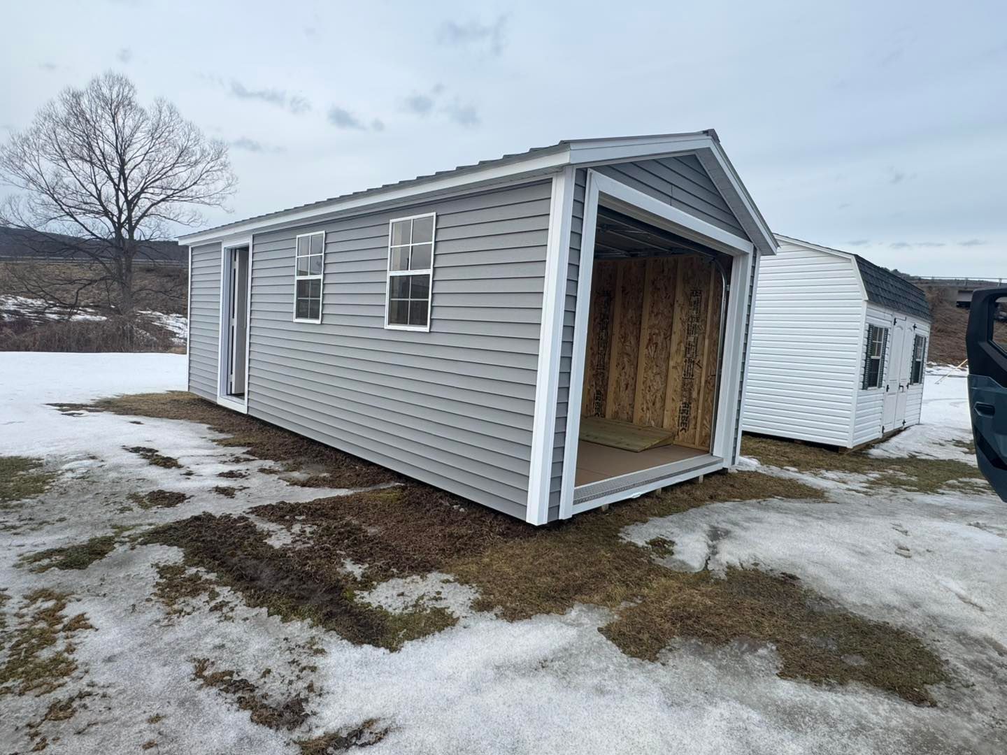 A shed with a garage attached to it is sitting in the snow.