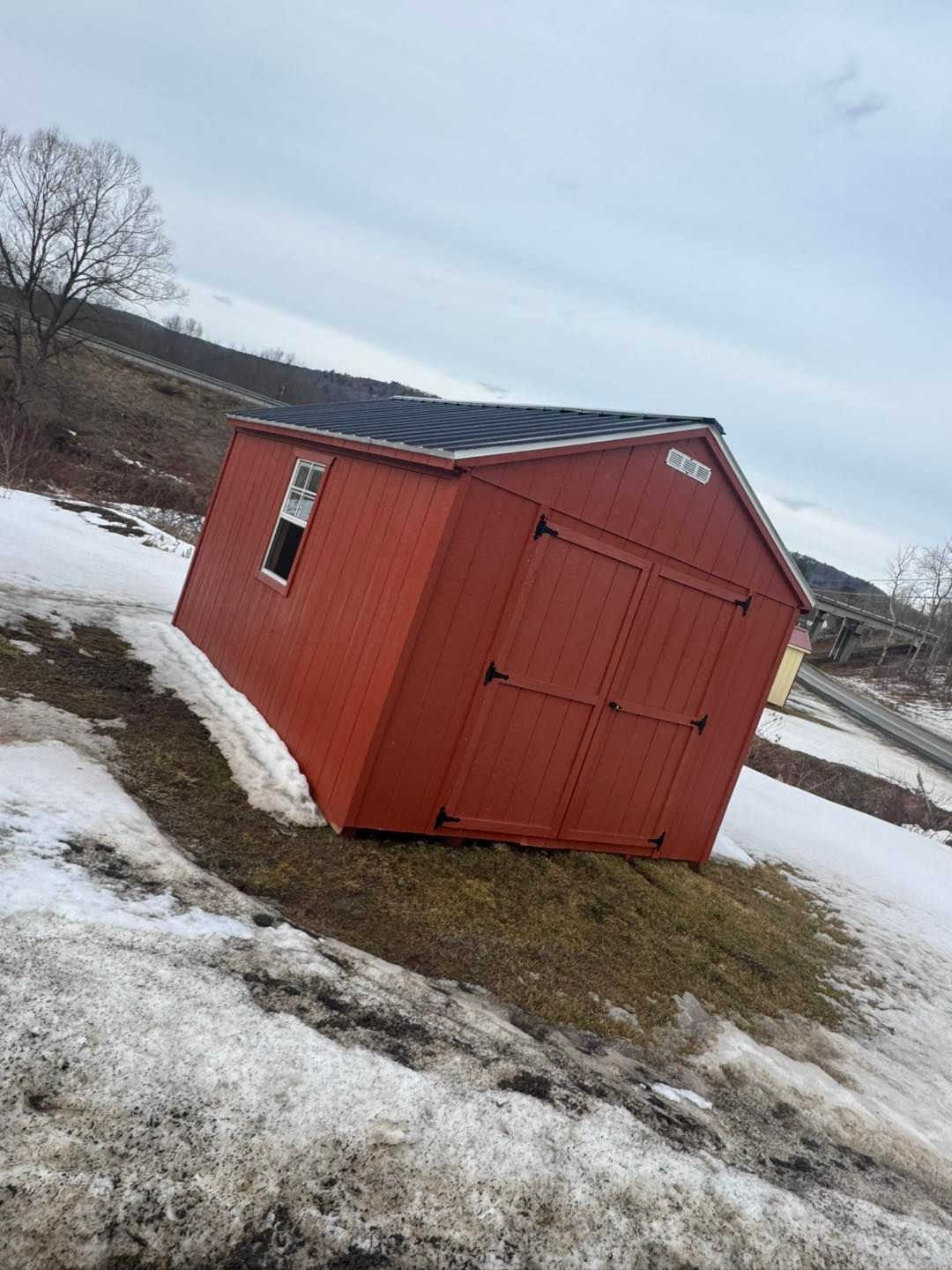 A red shed is sitting on top of a snow covered field.