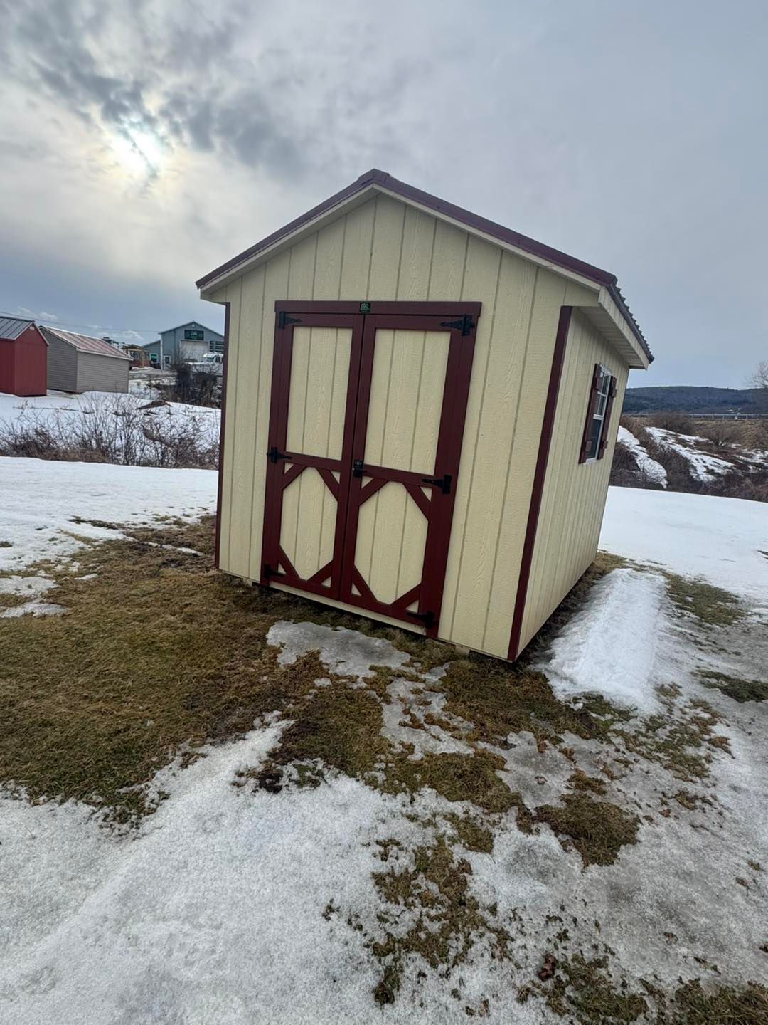 A small shed is sitting in the middle of a snowy field.