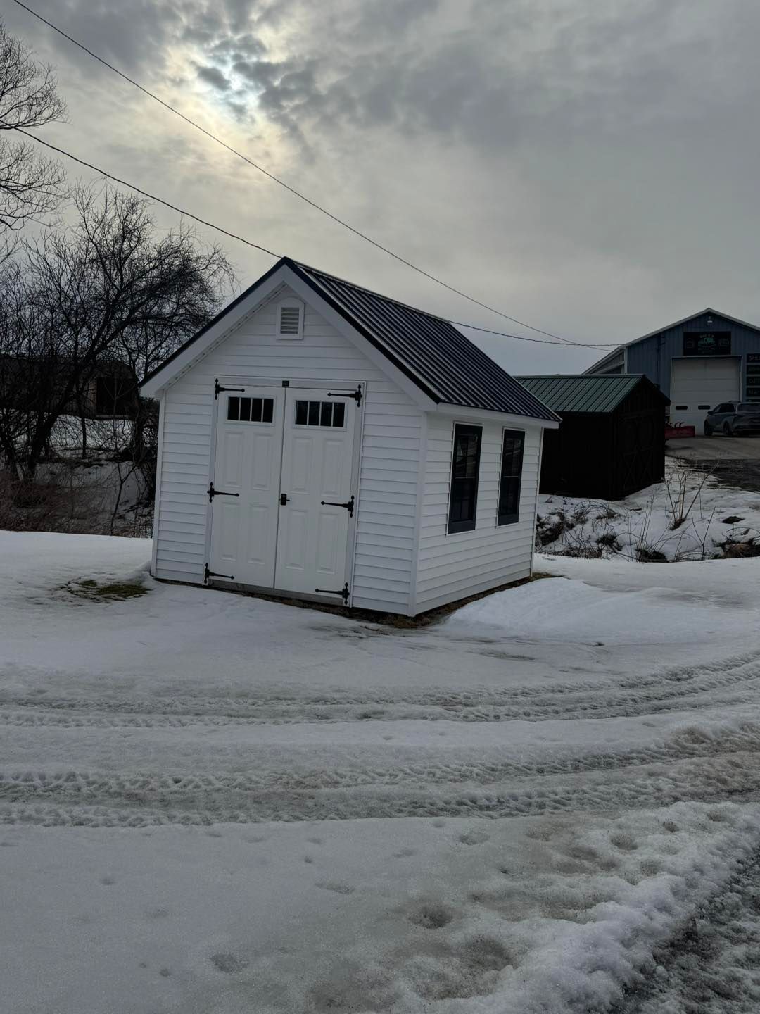 A small white shed is sitting in the middle of a snowy field.