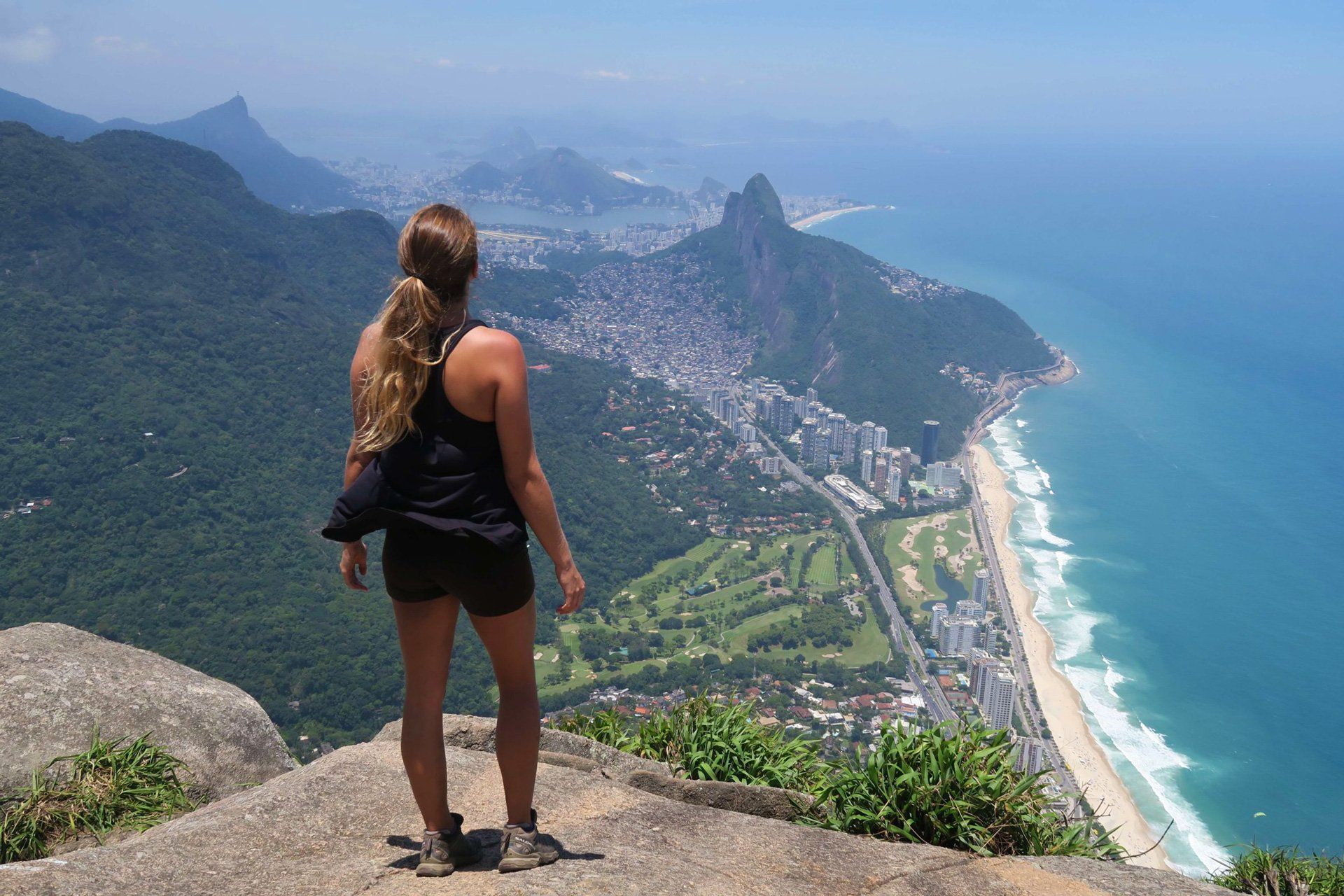 a girl looking at the views from the top of Gavea mountain
