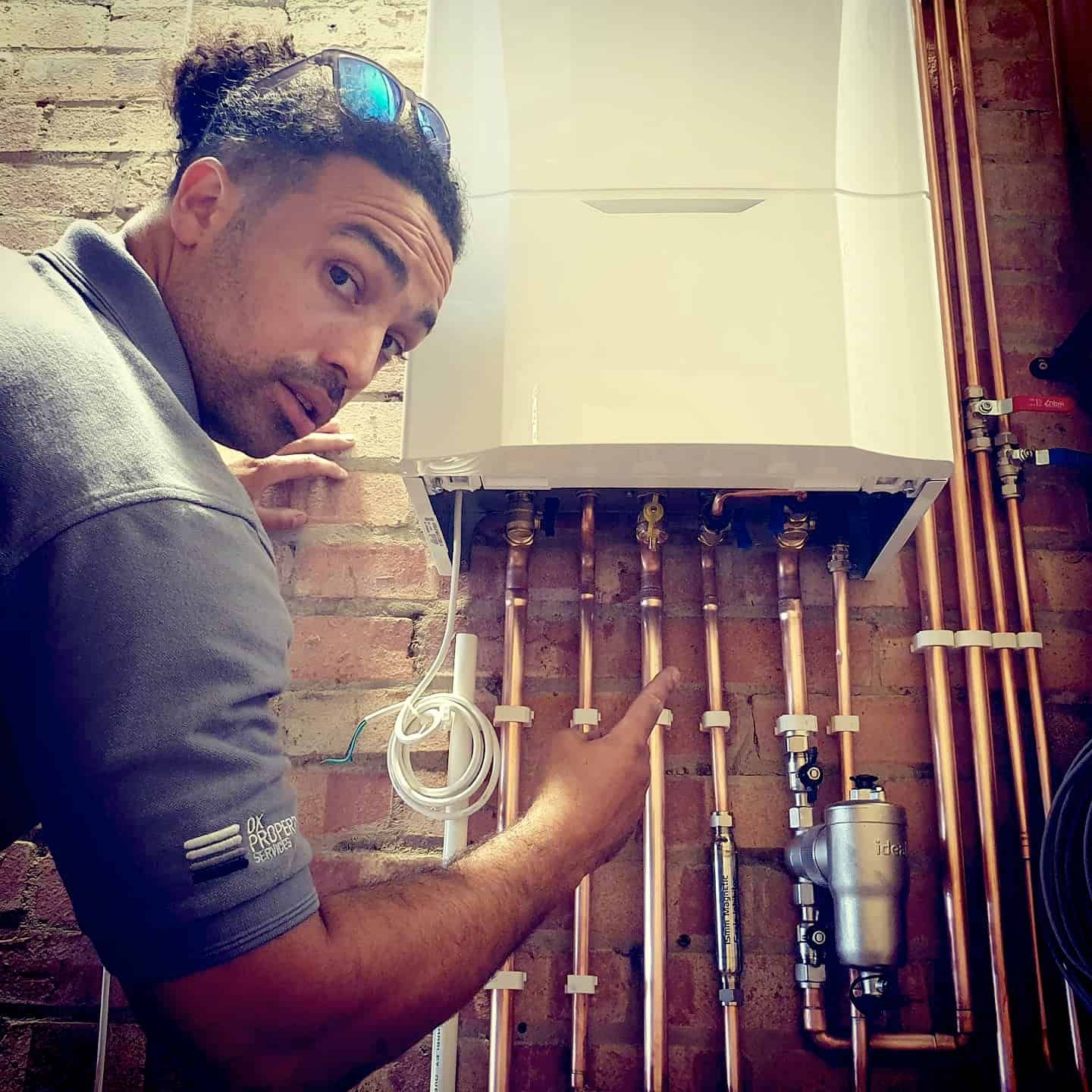 A man is standing in front of a boiler and pointing at it.
