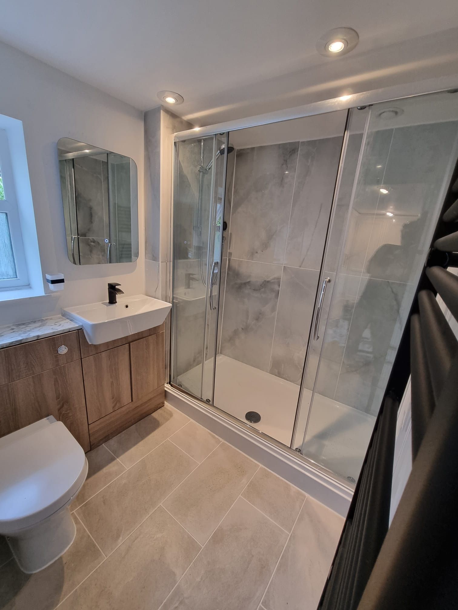 A bathroom with a toilet , sink , shower and mirror.