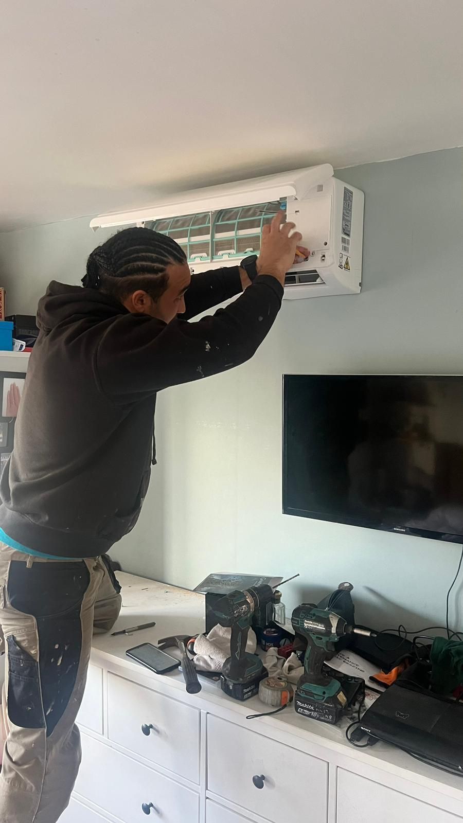 A man is installing an air conditioner in a living room.