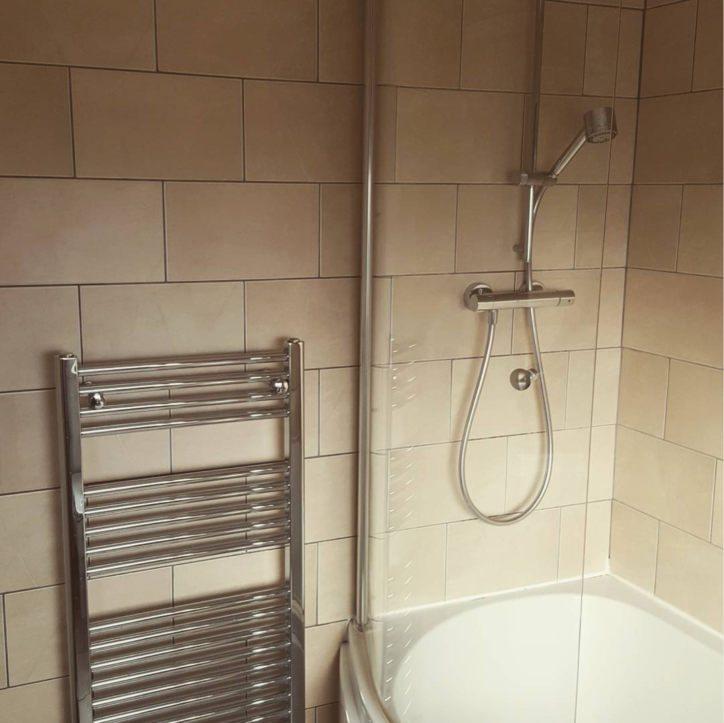 A bathroom with a shower and a towel rack