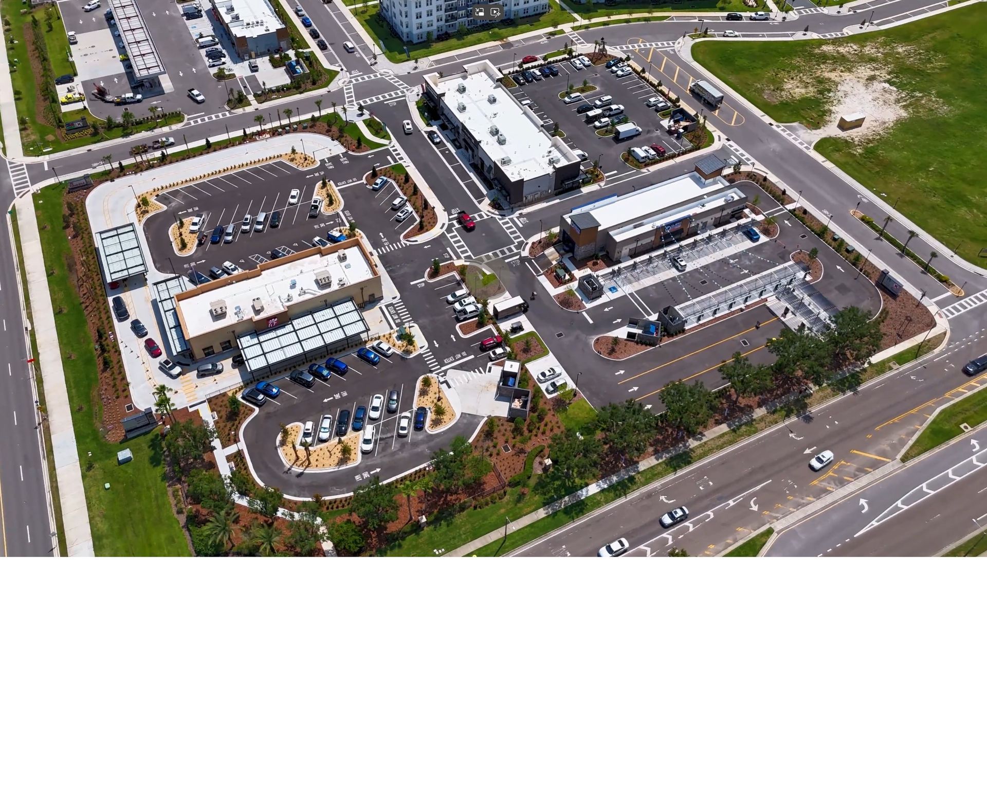 An aerial view of a lush green field surrounded by trees and a road.