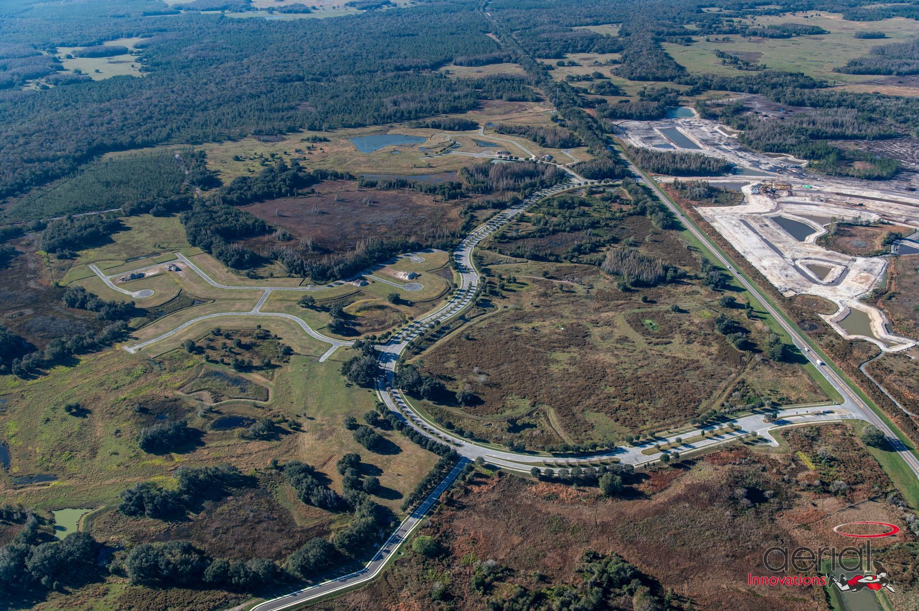 An aerial view of a lush green field surrounded by trees and a road.