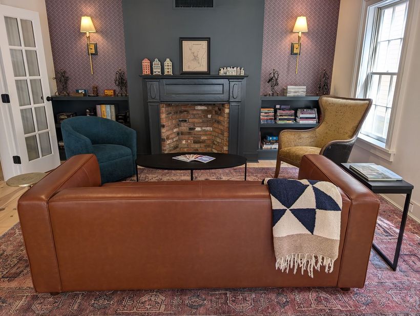 a seating room with large leather couch, a black coffee table and two club chairs