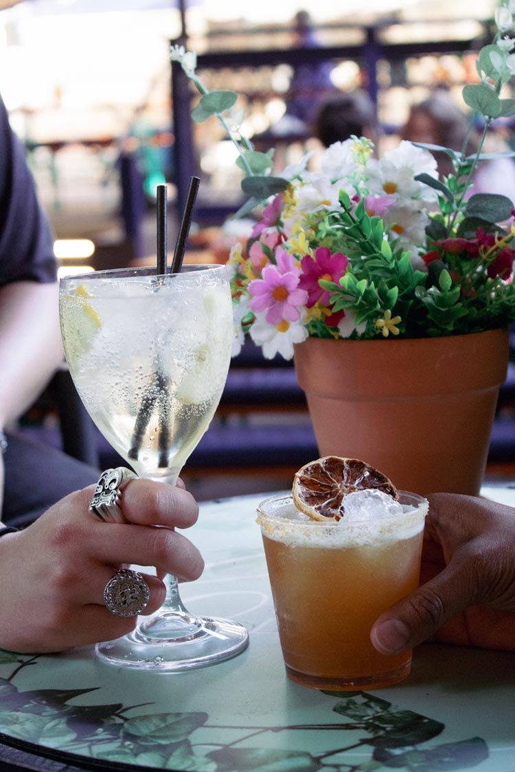 Two drinks are sitting on a bar next to each other.