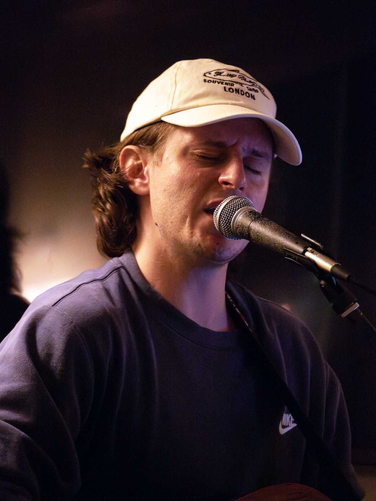 A man sings and plays the guitar in a restaurant.