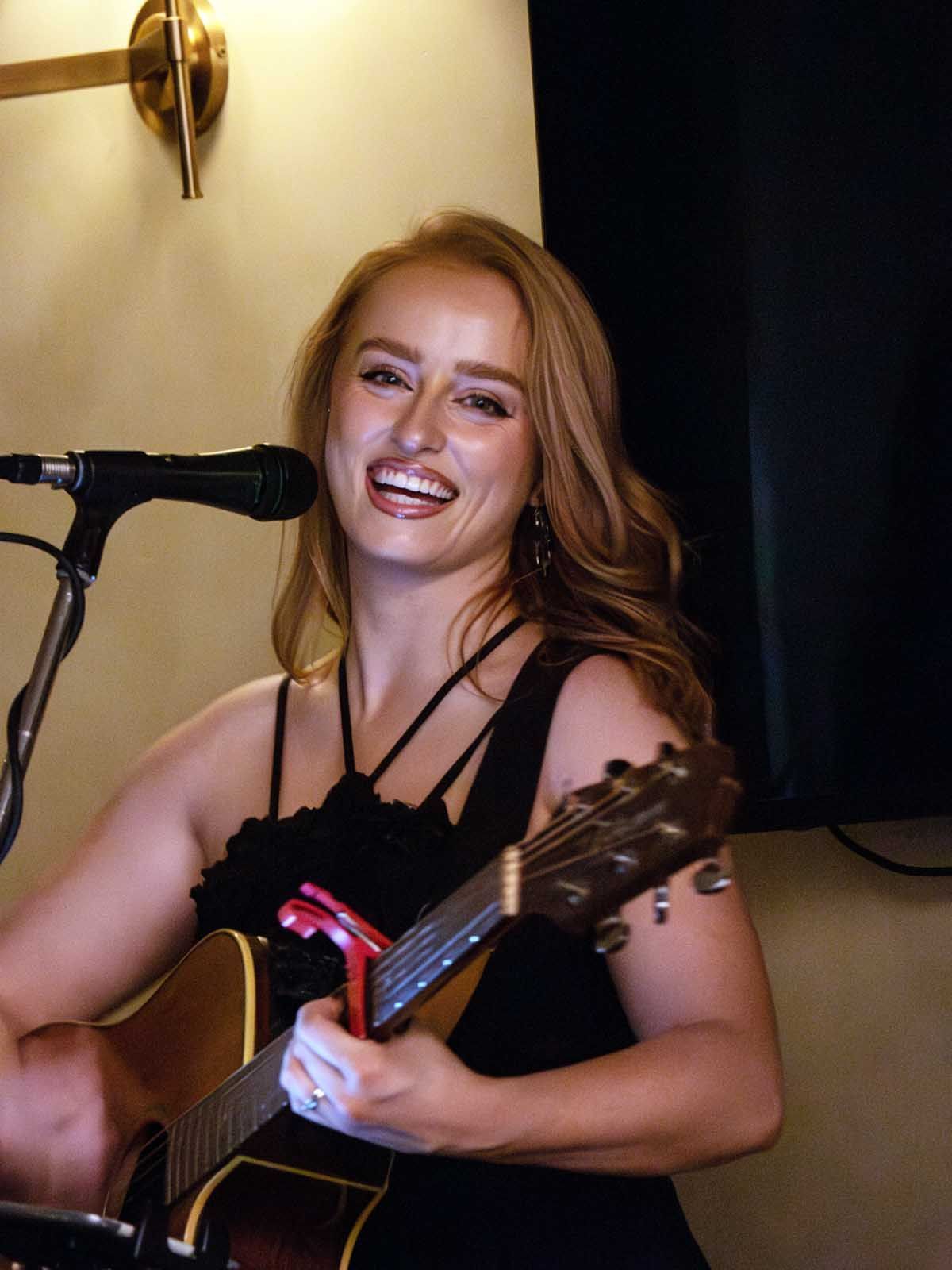 A lady singer plays guitar at a restaurant.
