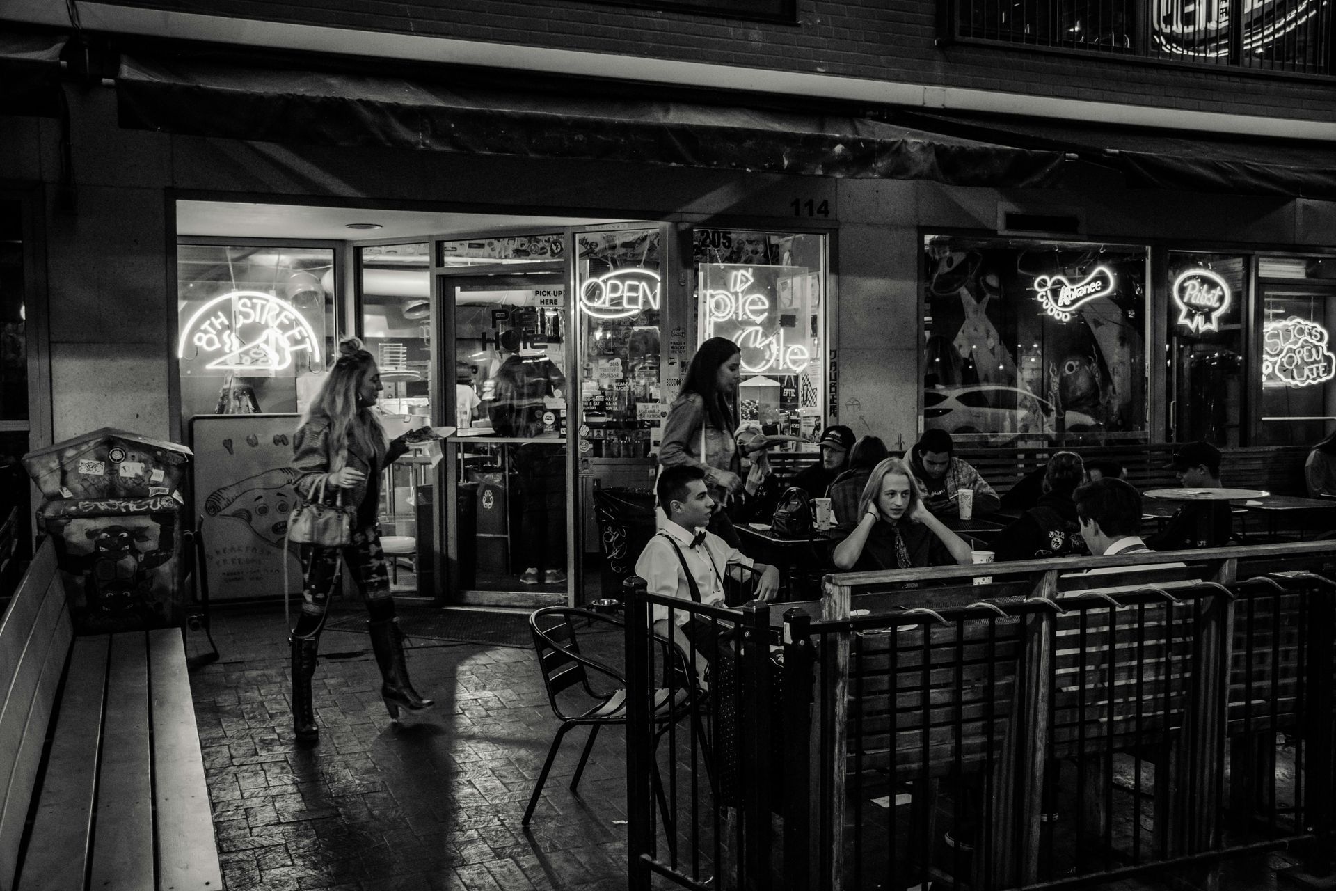 A black and white photo of people sitting at tables outside of a restaurant.