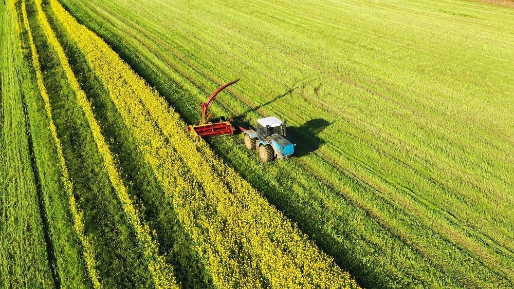 A Blue Tractor Harvesting A Field — NDC Earthworks in Gympie, QLD