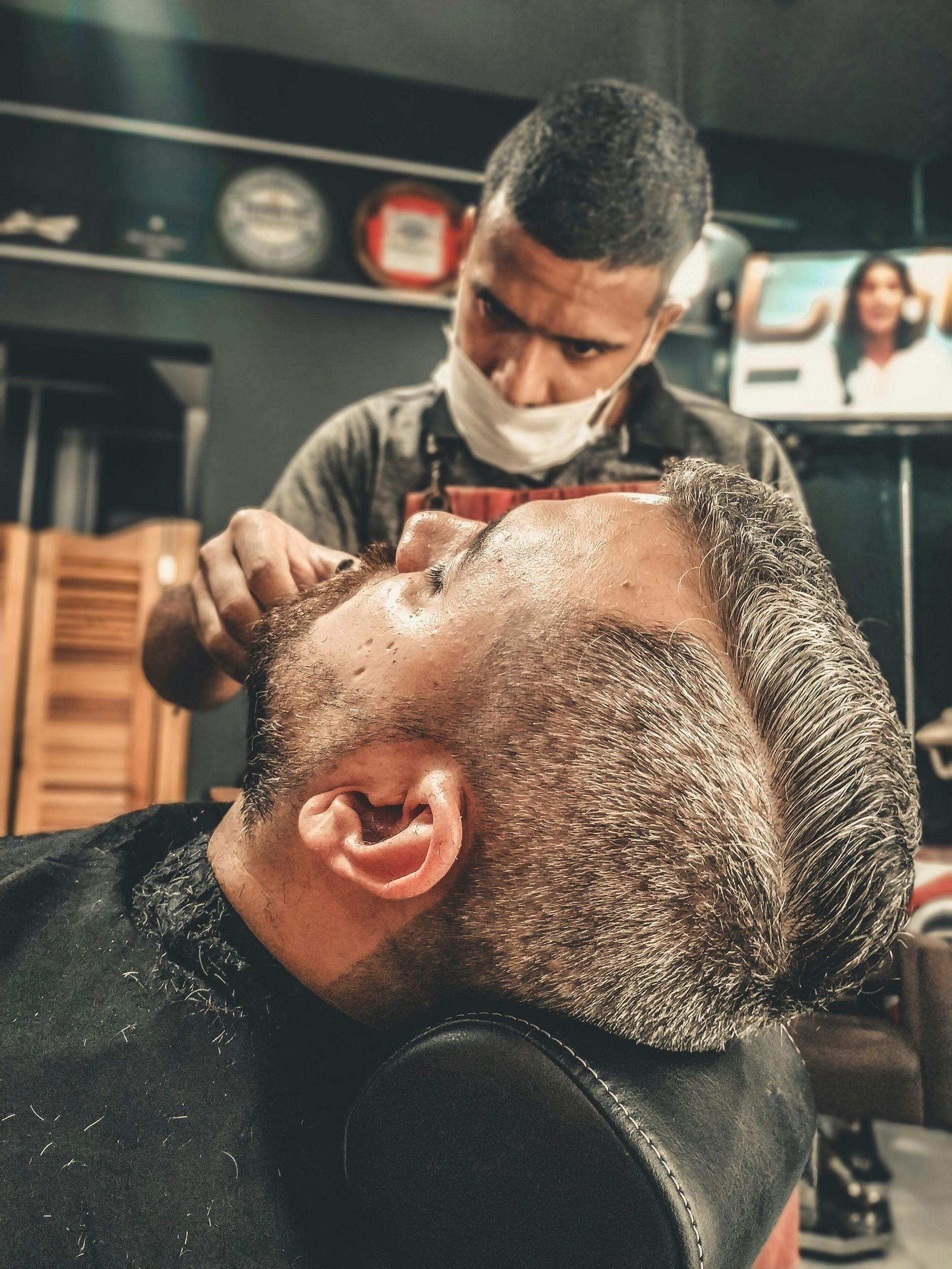 A man is getting his beard shaved by a barber
