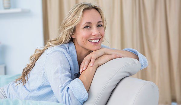 Happy woman sitting on the couch at home in CA