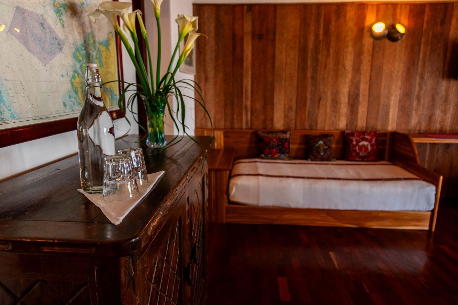 Un dormitorio con una cama, una cómoda, un jarrón de flores y un mapa en la pared. Tzampoc Resort