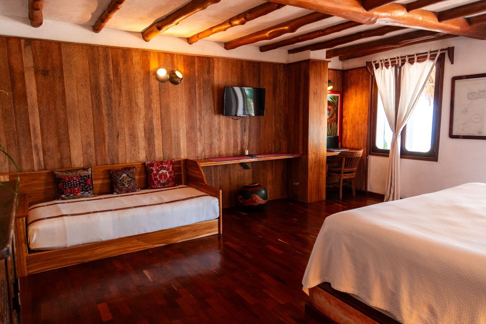 Una habitación de hotel con cama, sofá, escritorio y televisión. Tzampoc Resort