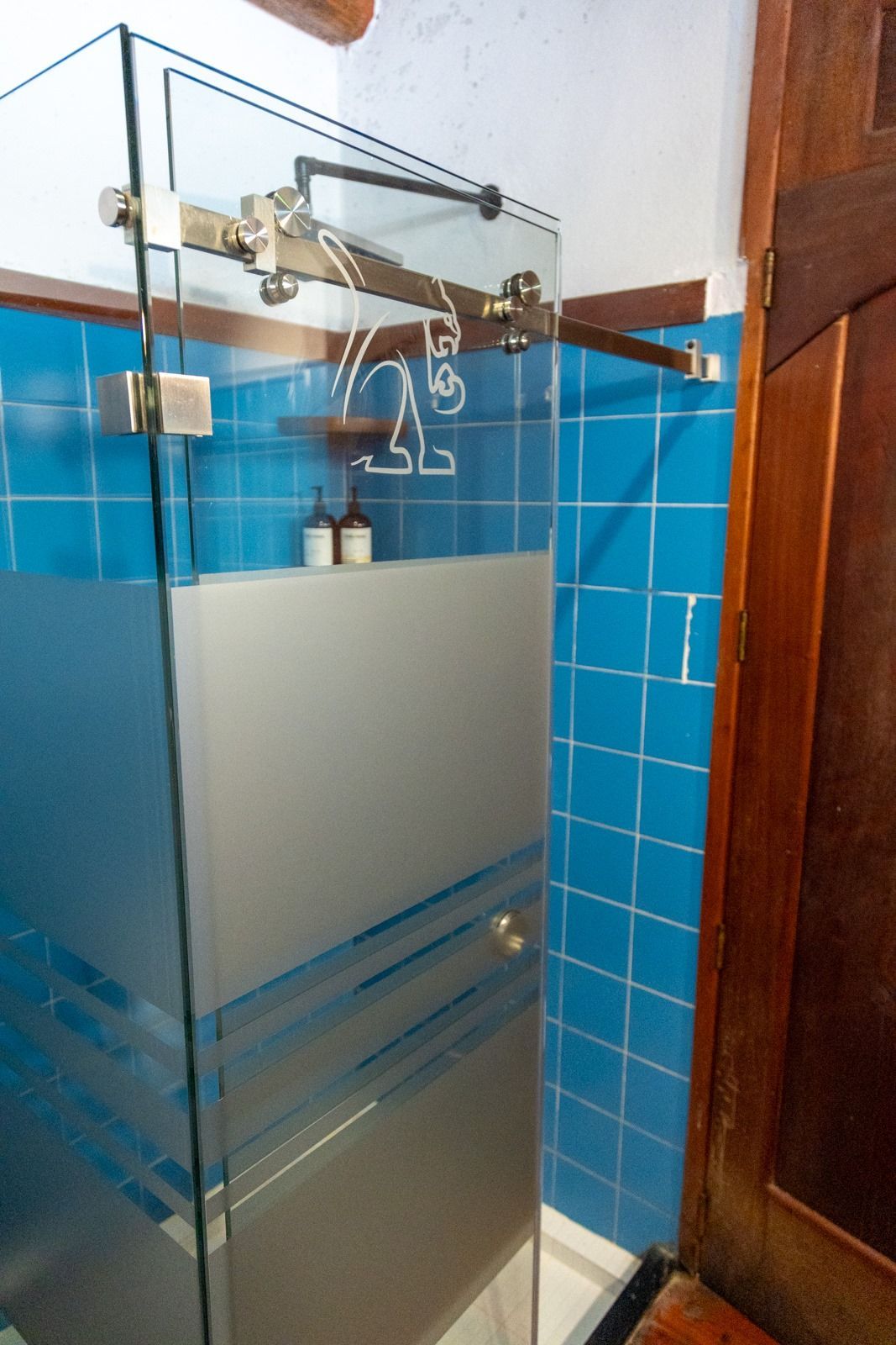 Un baño con azulejos azules y una puerta de ducha de cristal. Tzampoc Resort