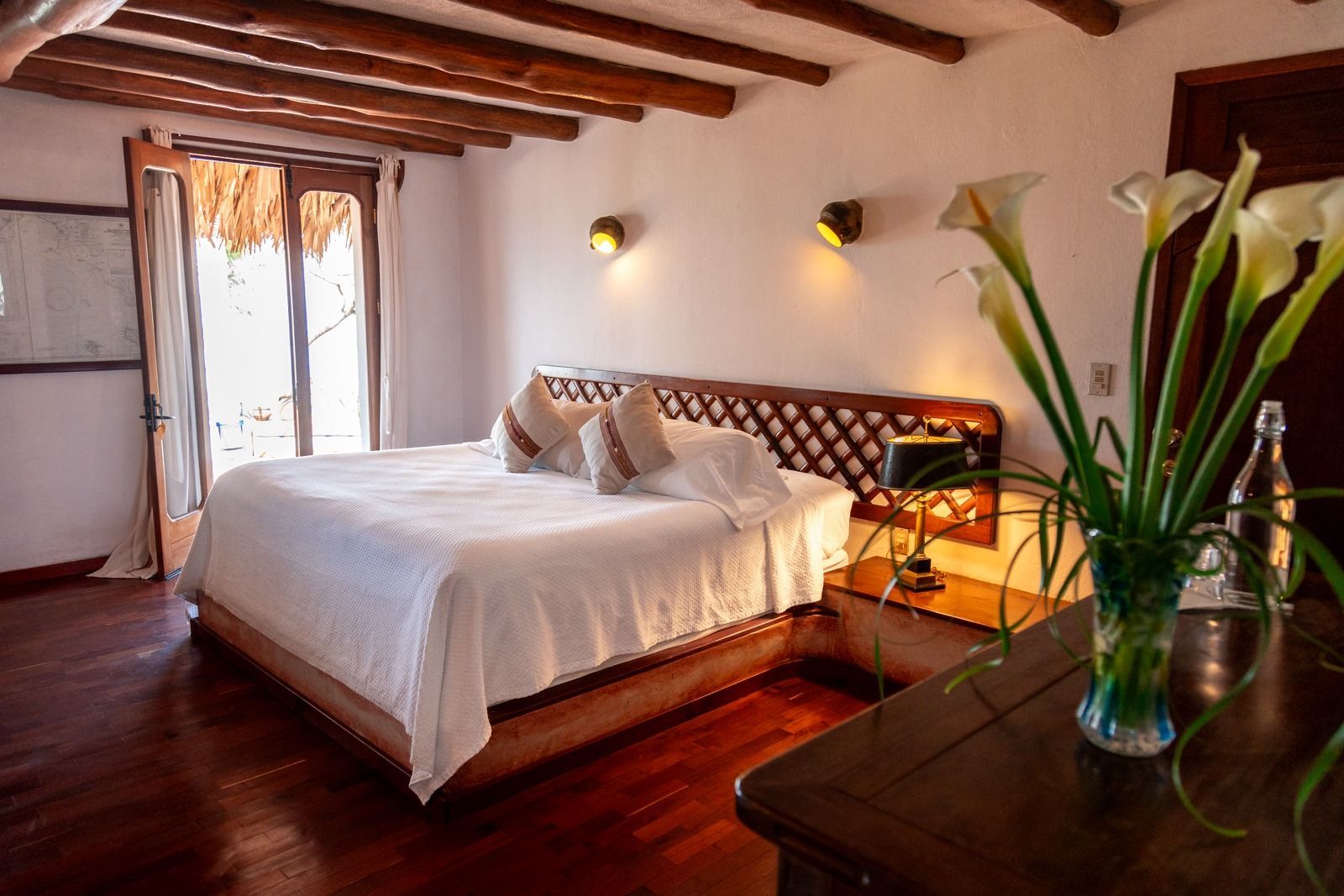 Un dormitorio con una cama grande y un jarrón de flores sobre la mesa. Tzampoc Resort