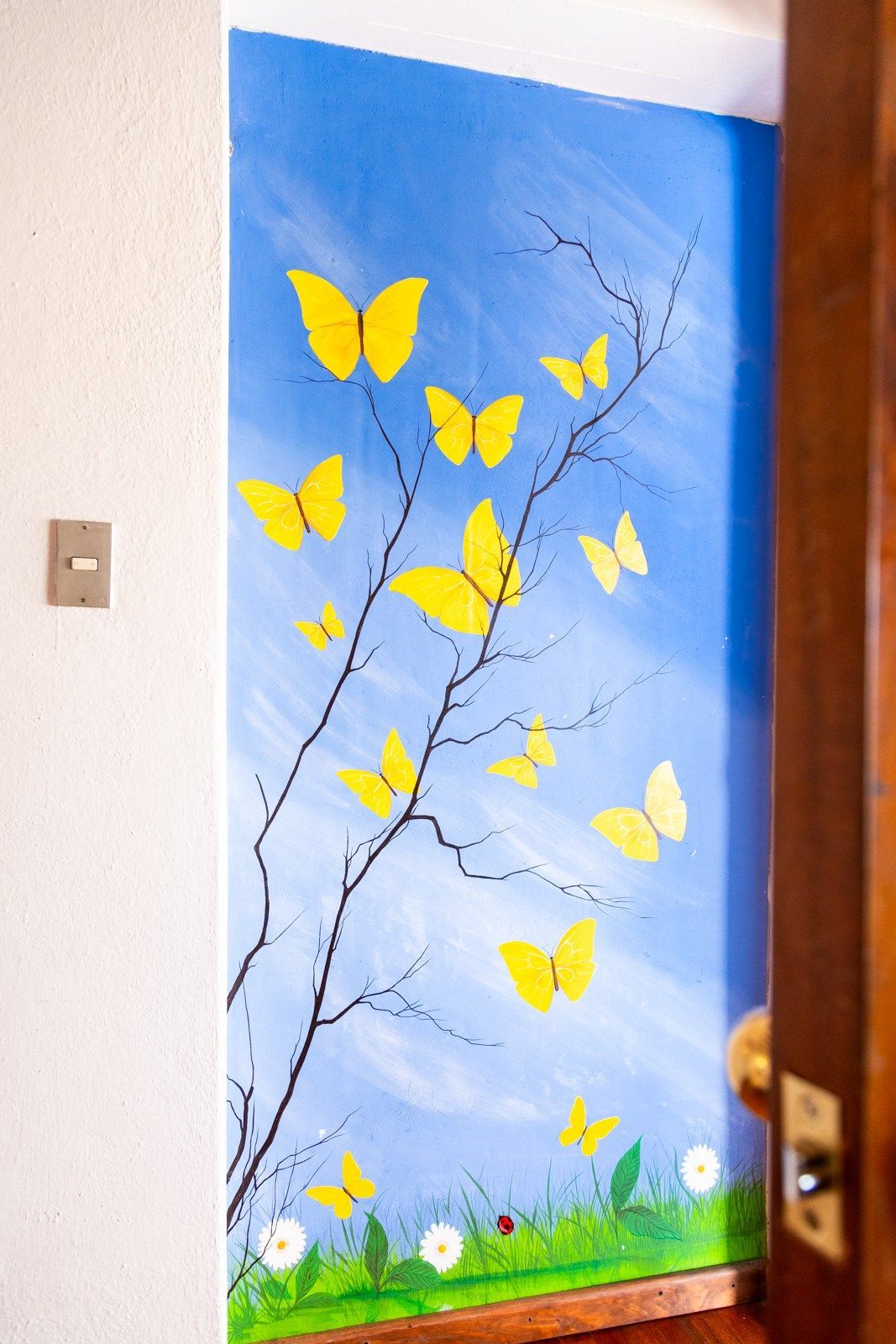 Una pintura de mariposas amarillas en la rama de un árbol.