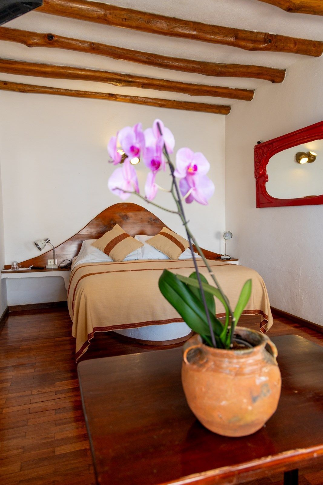 Una habitación con una cama y un jarrón de flores sobre una mesa.