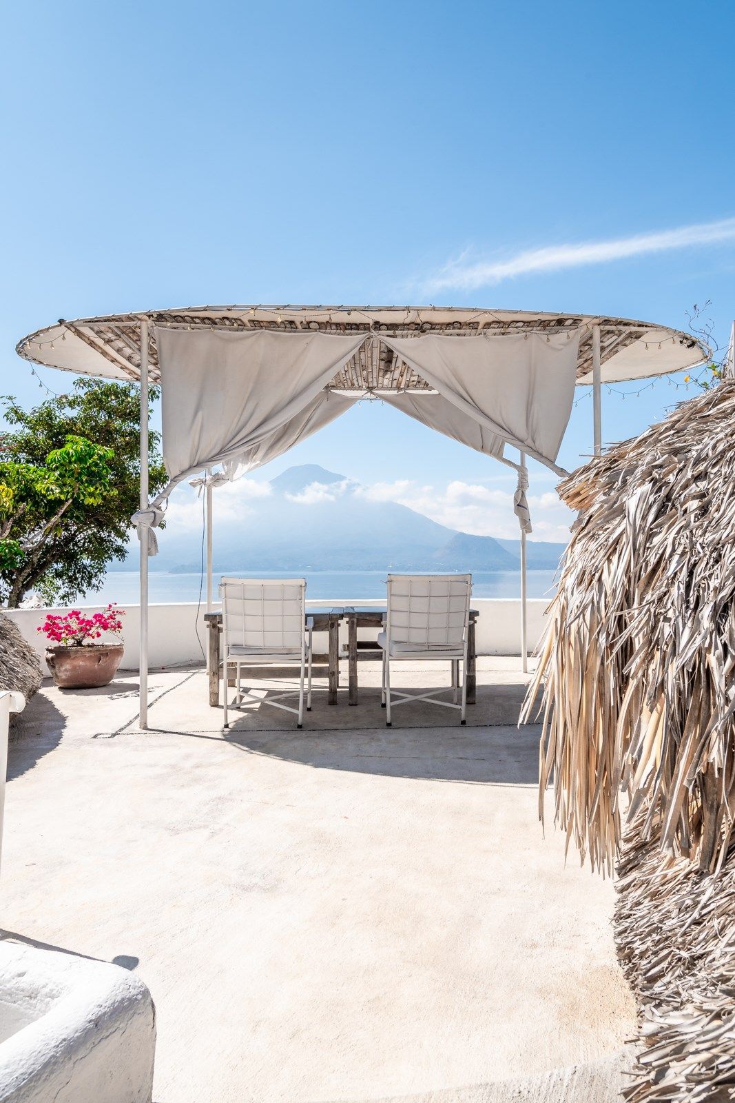Un patio con una mesa y sillas bajo un dosel con vista al océano. Tzampoc Resort