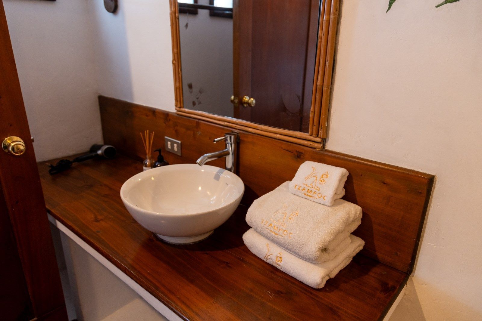 Un baño con lavabo, espejo y toallas en el mostrador.