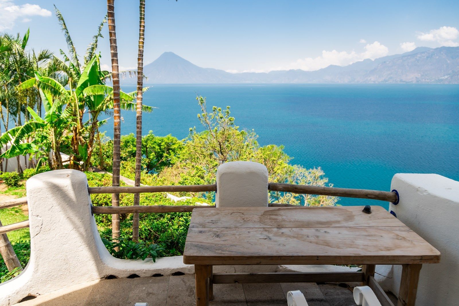 Una mesa de madera está sentada en un balcón con vista al lago. Tzampoc Resort