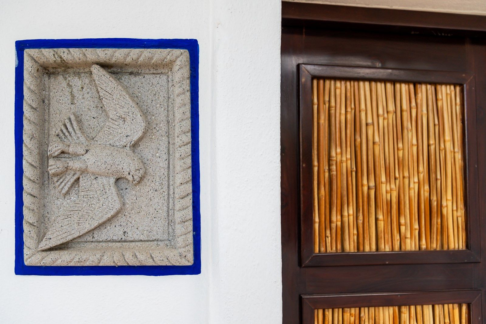 Una placa en una pared al lado de una puerta de bambú. Tzampoc Resort