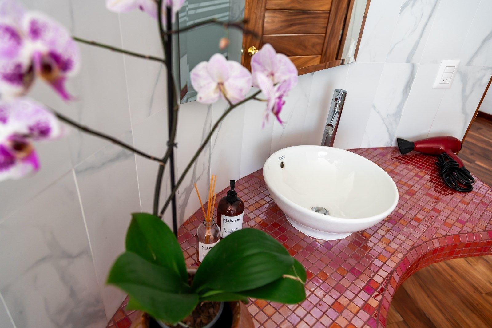 Un baño con un lavabo y una planta en maceta sobre la encimera.