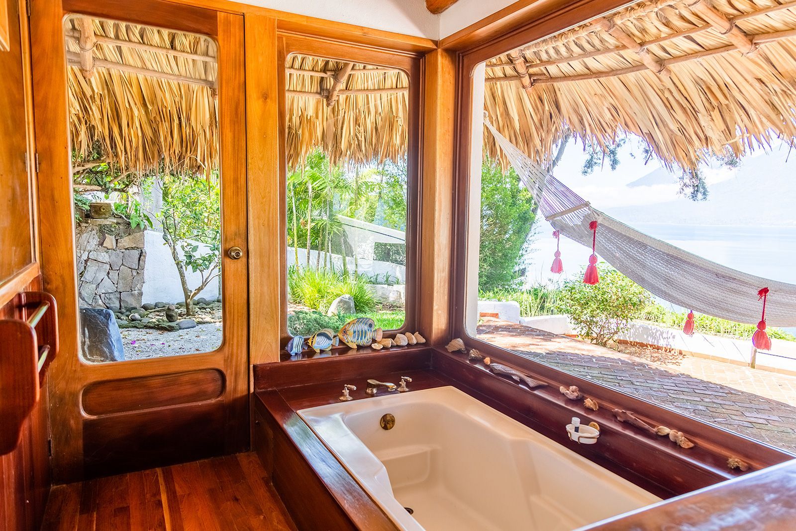 Un baño con bañera y una hamaca en la ventana.