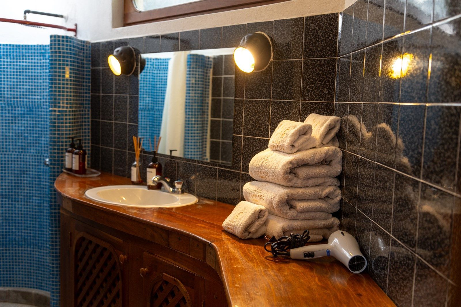 Un baño con lavabo, espejo, toallas y secador de pelo. Tzampoc Resort