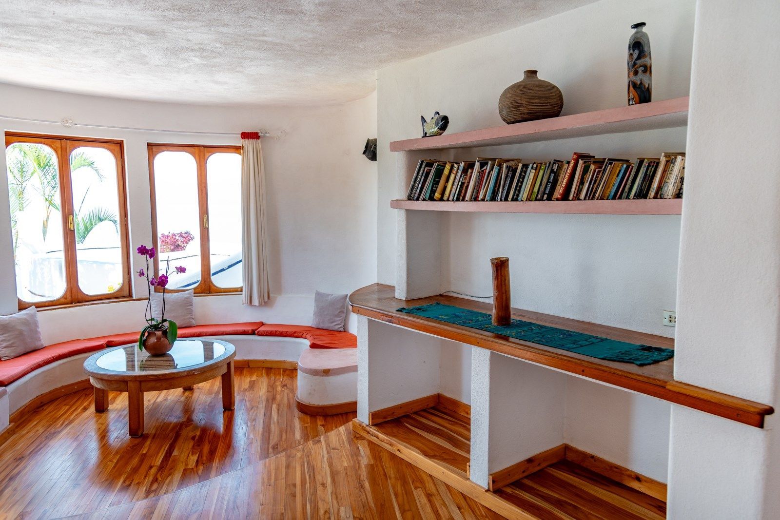 Una sala de estar con pisos de madera, una mesa y una estantería llena de libros. Tzampoc Resort