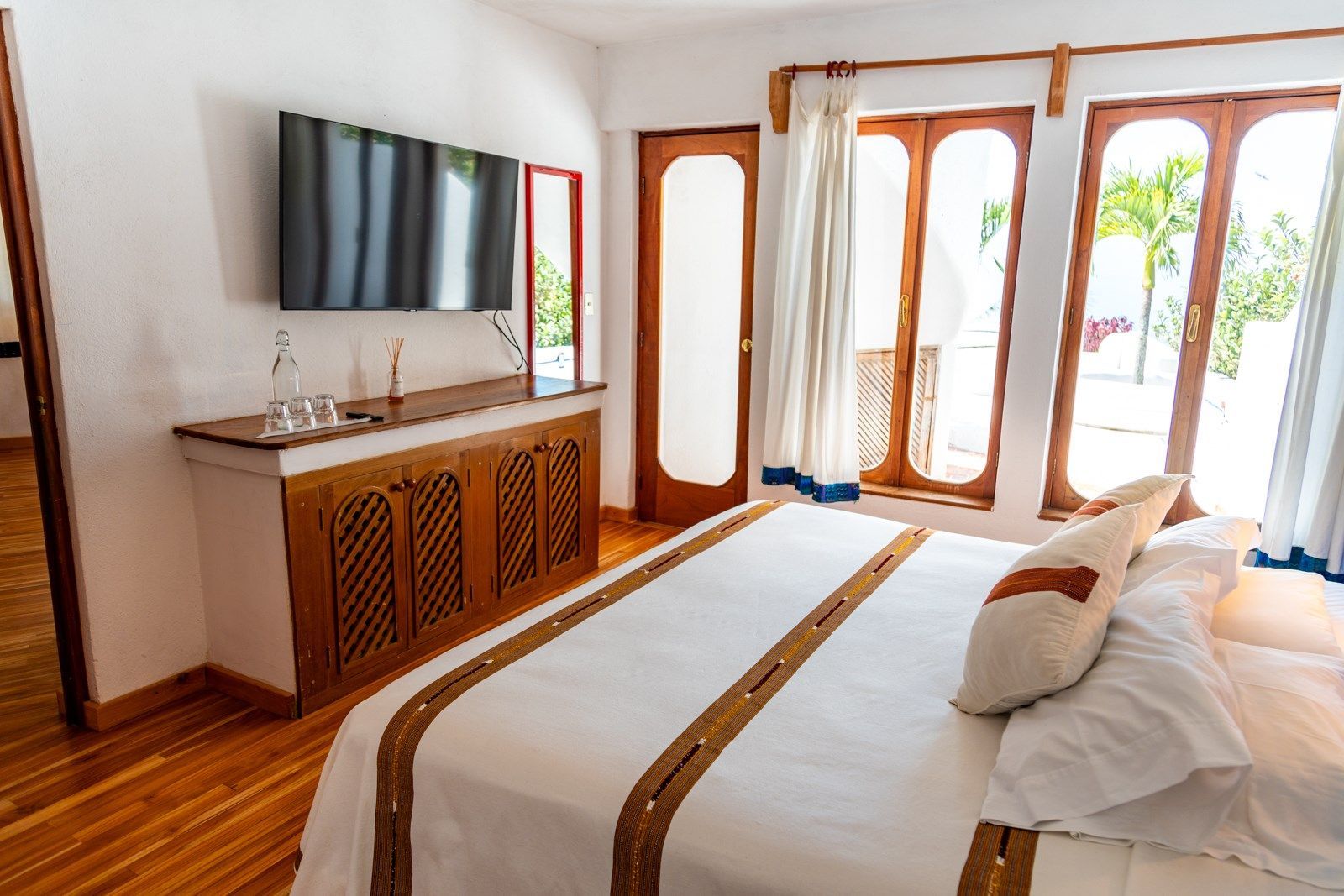 Una habitación de hotel con una cama tamaño king, un televisor de pantalla plana y una ventana grande. Tzampoc Resort