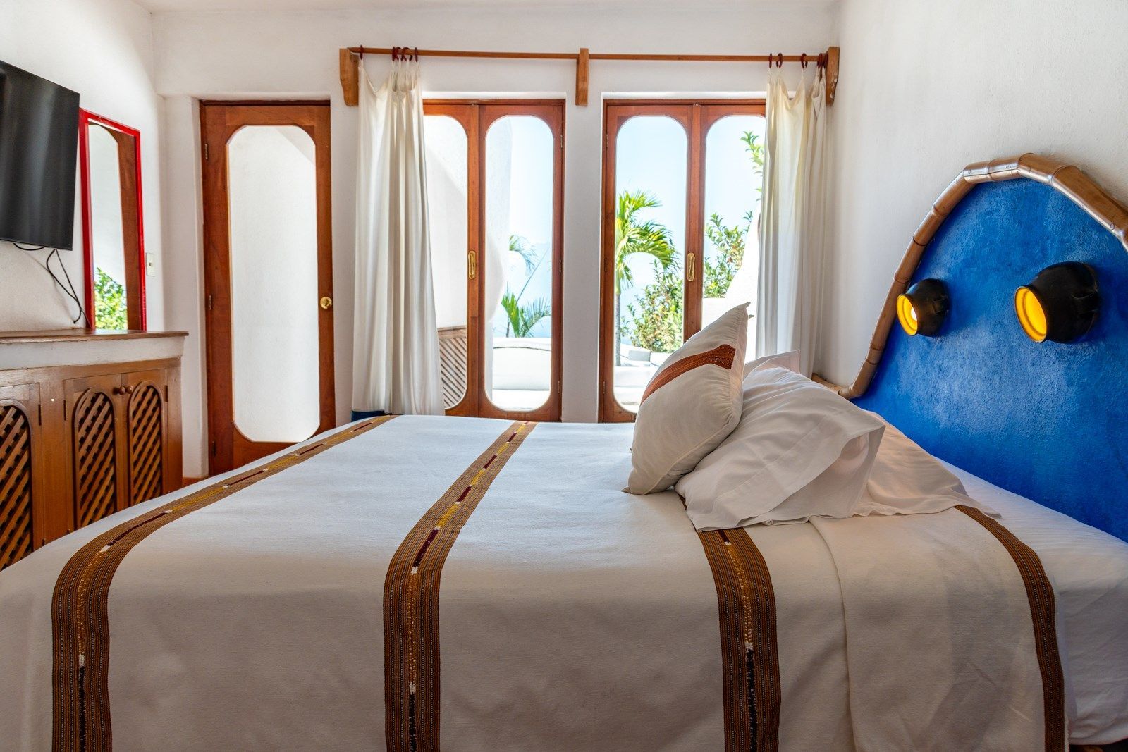 Una habitación de hotel con una cama tamaño king y un cabecero azul. Tzampoc Resort