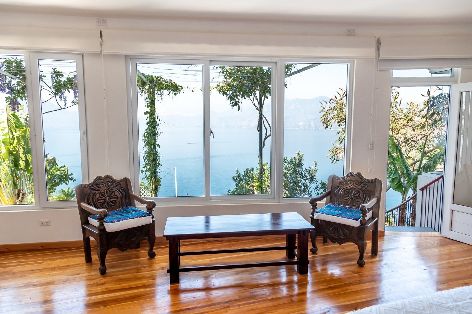 Una sala de estar con mesa y sillas y vista al mar.