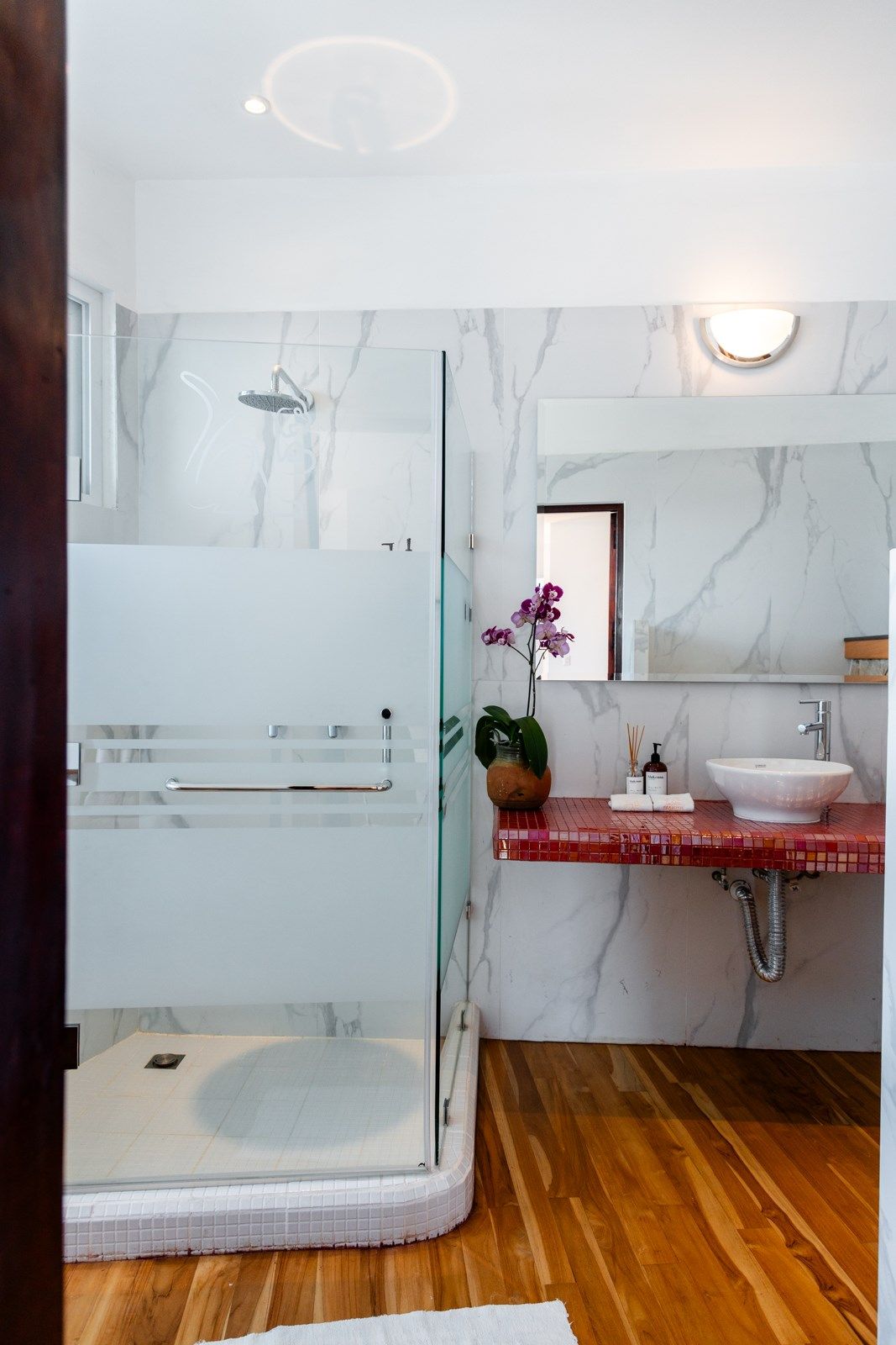 Un baño con lavabo, ducha y espejo.