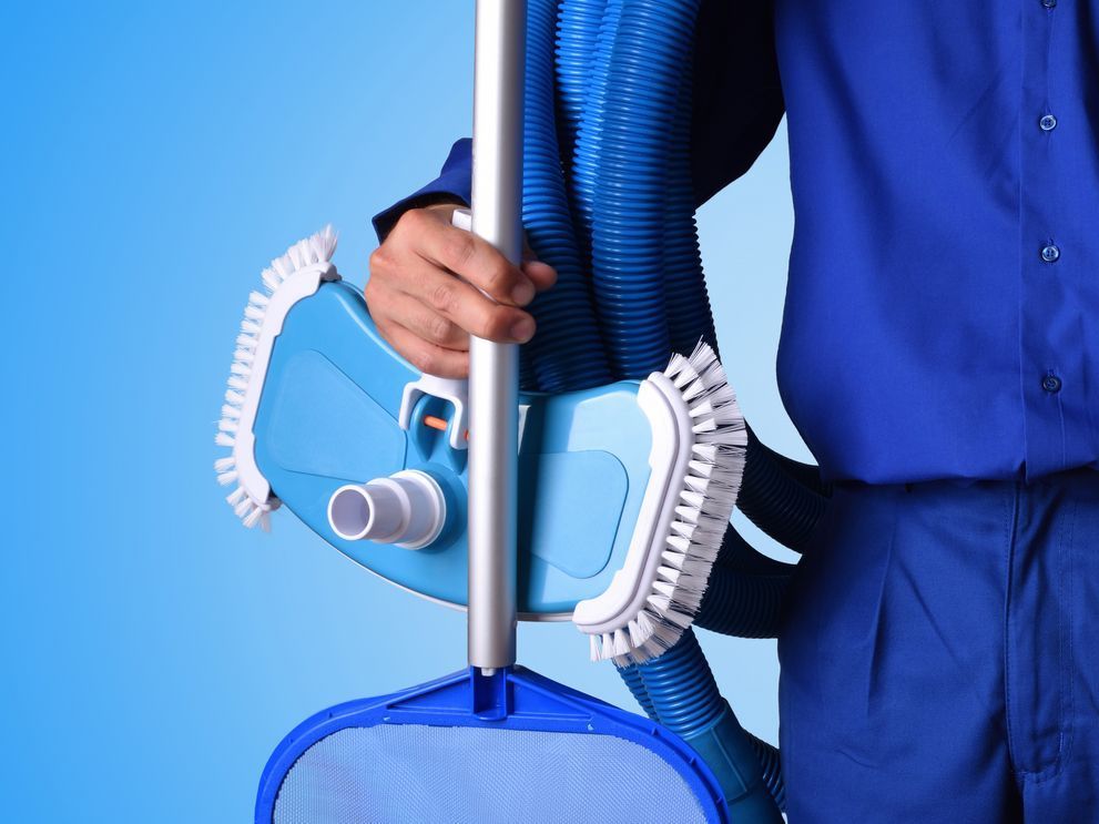 A man in a blue shirt is holding a mop and a bucket.