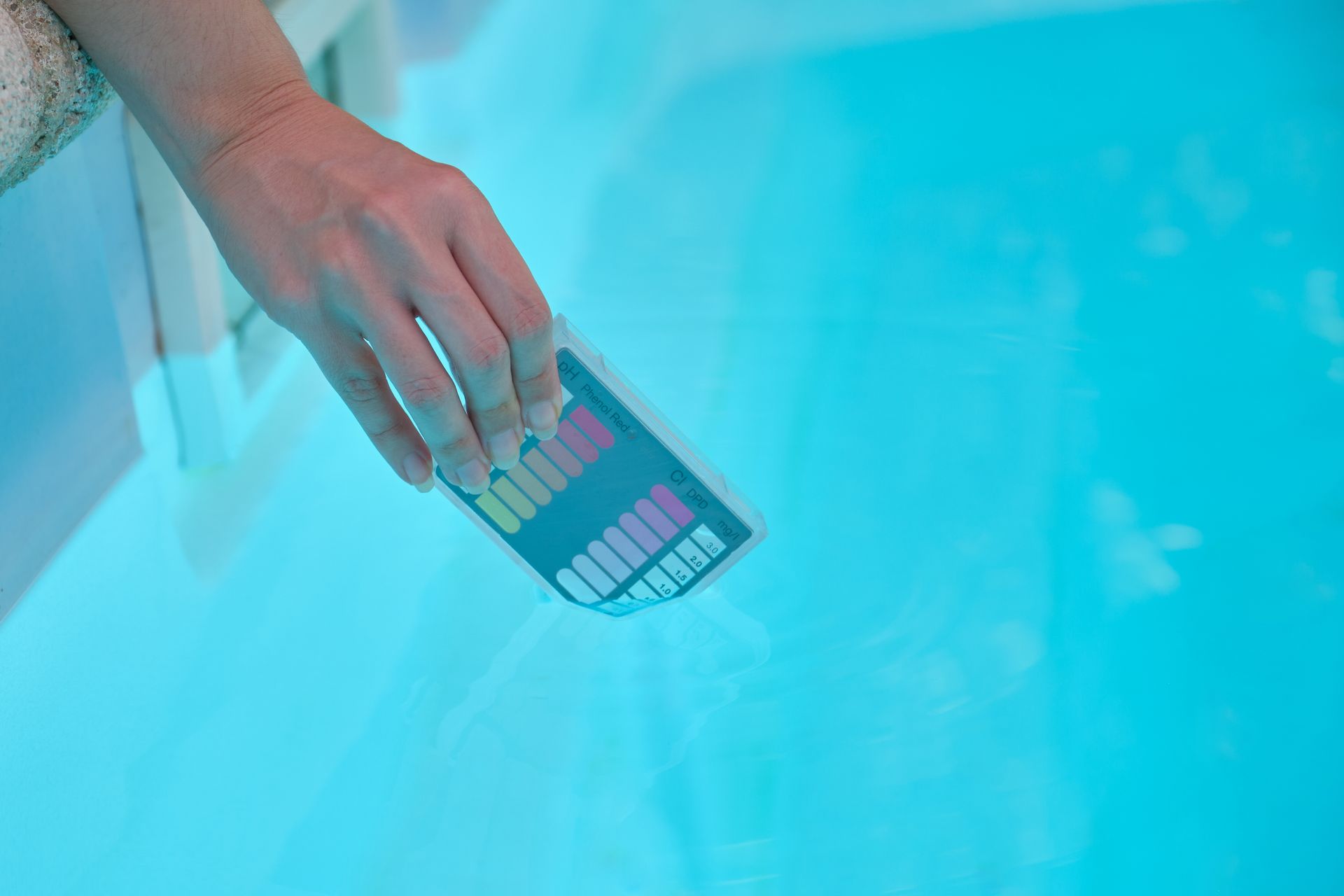 A person is taking a test of the water in a swimming pool.