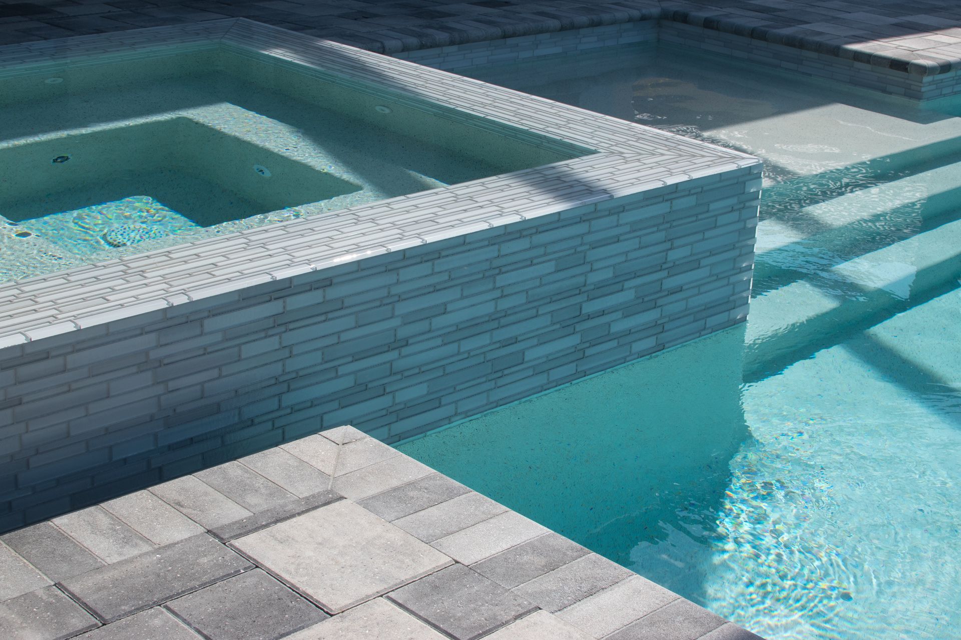 A swimming pool with a hot tub and stairs next to it.