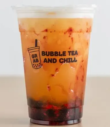 Bubble tea in clear plastic cup with red berry base and white foam top;