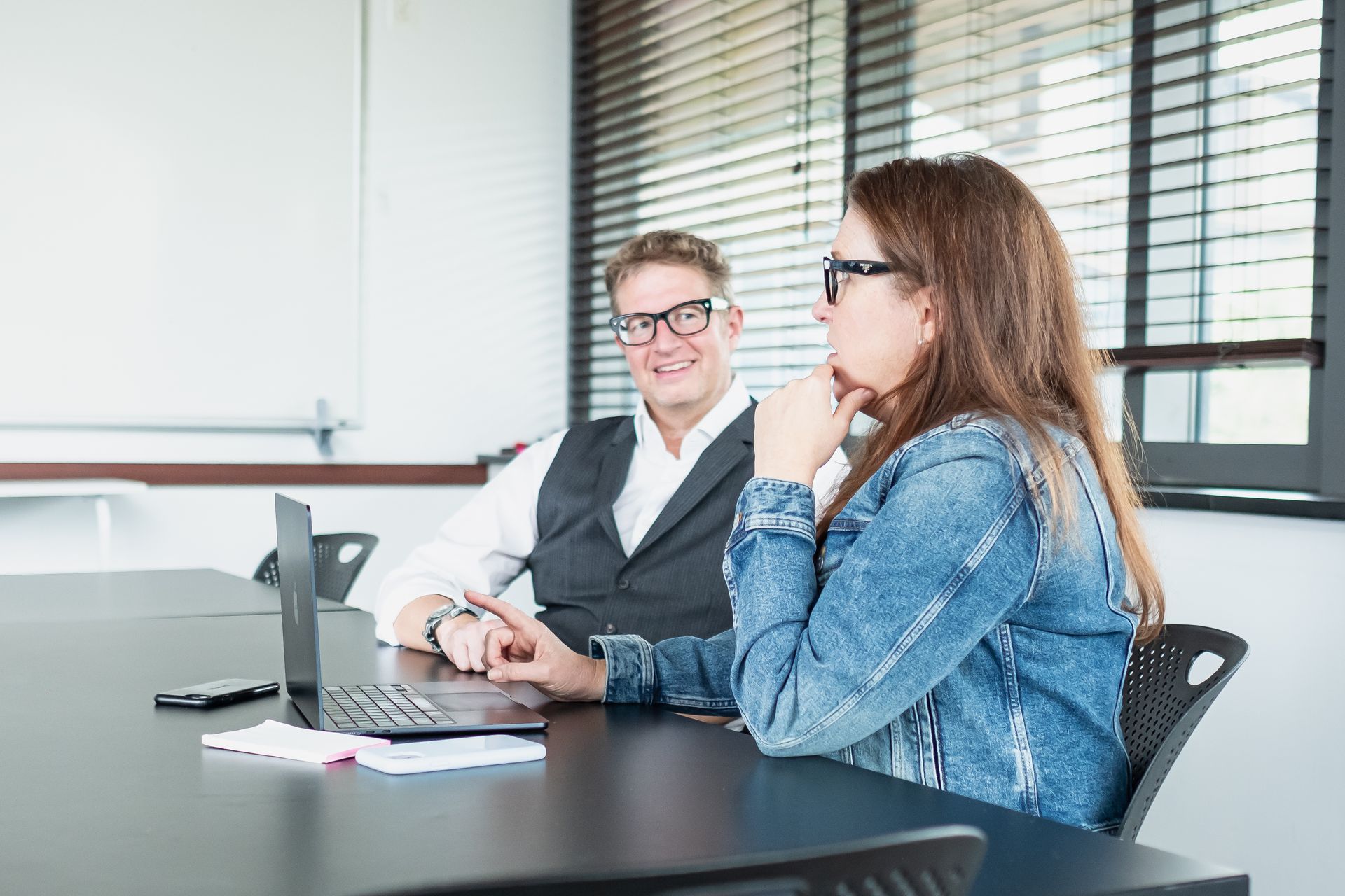 A woman is sitting at a desk with her head in her hands in front of a laptop computer.