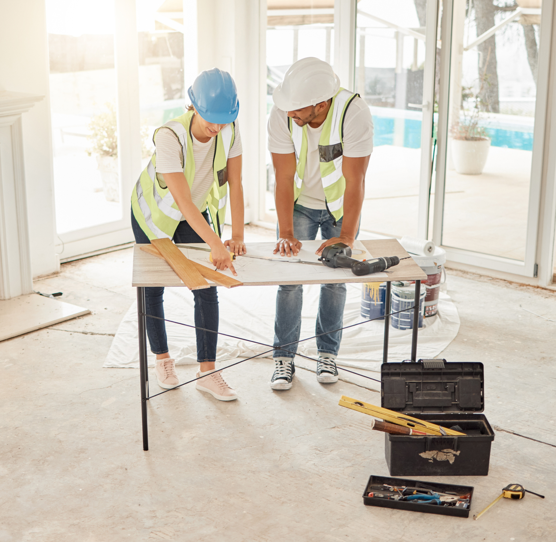 A man and a woman are standing at a table looking at a blueprint.