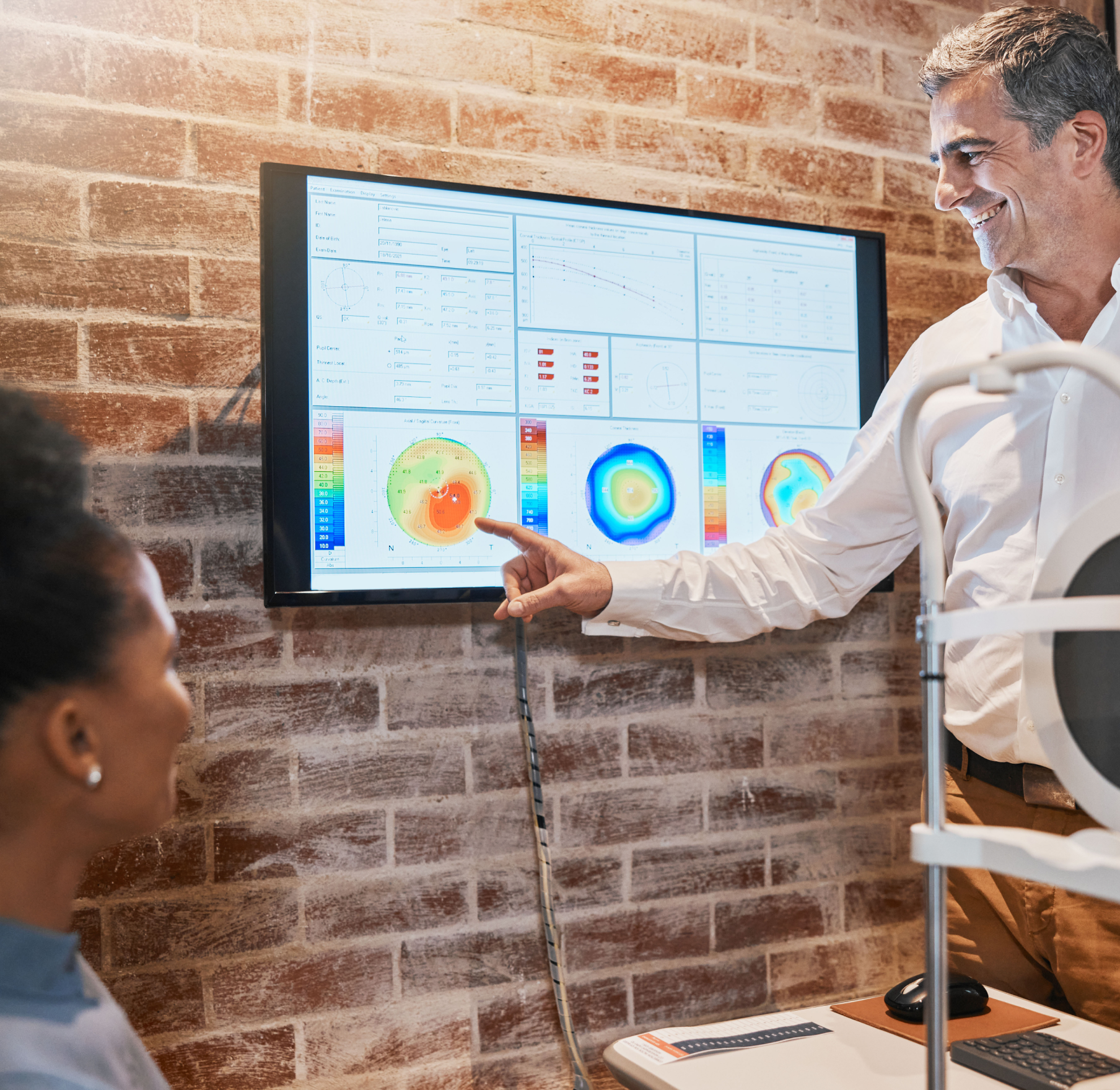 A man is pointing at a screen while talking to a woman.